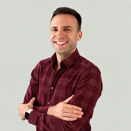 Portret Macieja Budzisza na jasnoszarym tle. Ma krótkie ciemne włosy. Ubrany jest w bordową koszulę w kratę, na nadgarstku ma smartwatch. Stoi z założonymi rękami i szeroko się uśmiecha, patrząc w obiektyw.